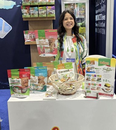 A Dulzura representative beside the brand product shelf and logo in the Puerto Rico pavilion.