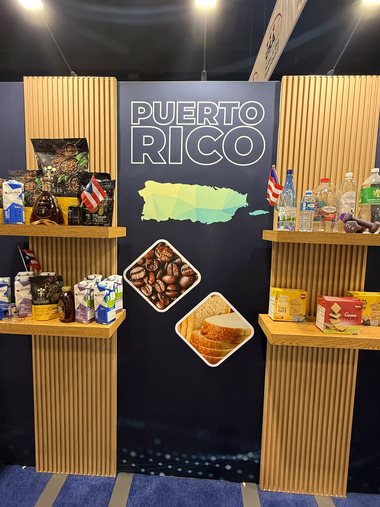 Puerto Rico pavilion wall with the PUERTO RICO wordmark, island graphic and wood-slat shelves of local products, built by Display America.