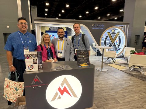 Four attendees standing together at a branded exhibition stand.