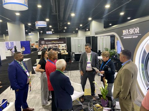 A group of attendees in conversation at the Xelsior branded exhibition stand.